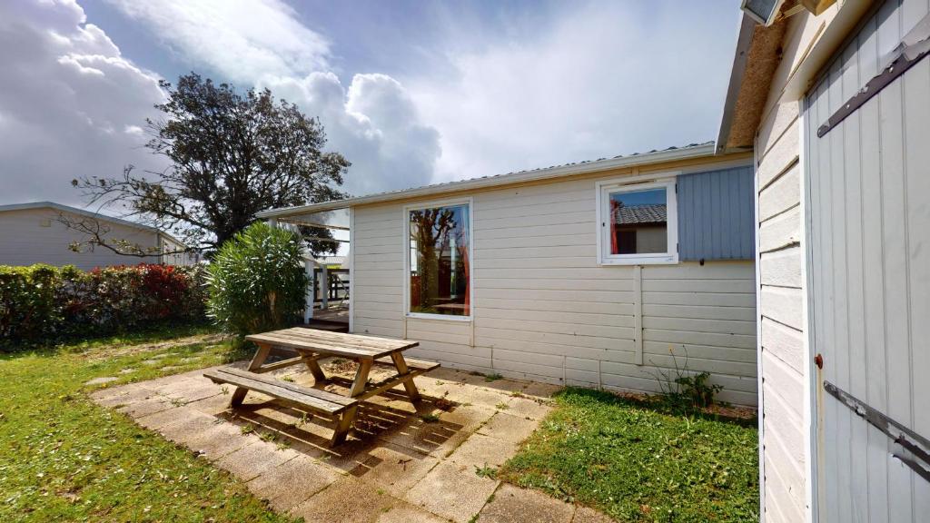 une table de pique-nique en bois devant une maison dans l'établissement Le Chalet de L Auzance - Piscine & Plage, à Brem-sur-Mer