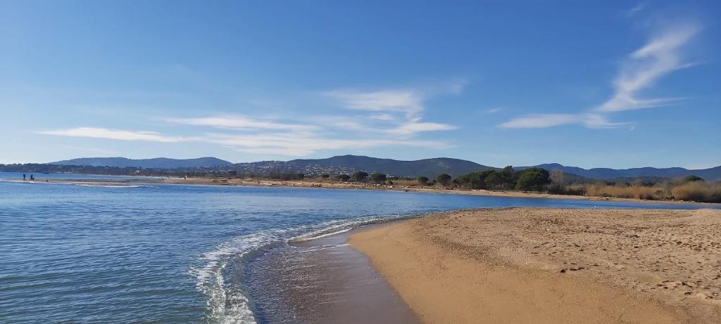 une plage avec de l'eau et des montagnes en arrière-plan dans l'établissement Residence Bord de mer, à Fréjus