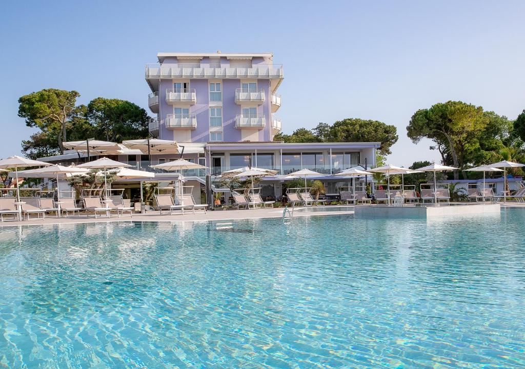 a swimming pool with chairs and umbrellas in front of a hotel at Fantinello Hotel in Caorle