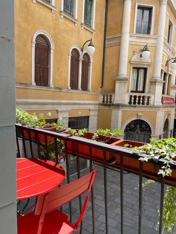 une table et des chaises rouges sur un balcon orné de plantes dans l'établissement Appartamento Al Malibran, à Venise