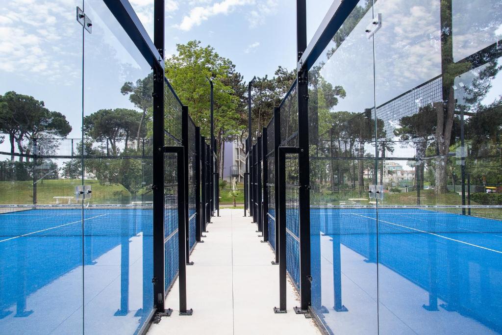 a tennis court with glass walls and a tennis at Fantinello Hotel in Caorle