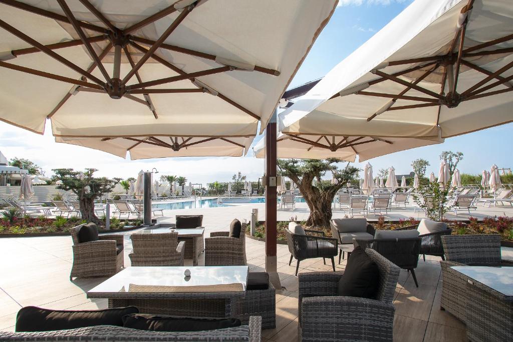 a patio with tables and umbrellas and a pool at Fantinello Hotel in Caorle