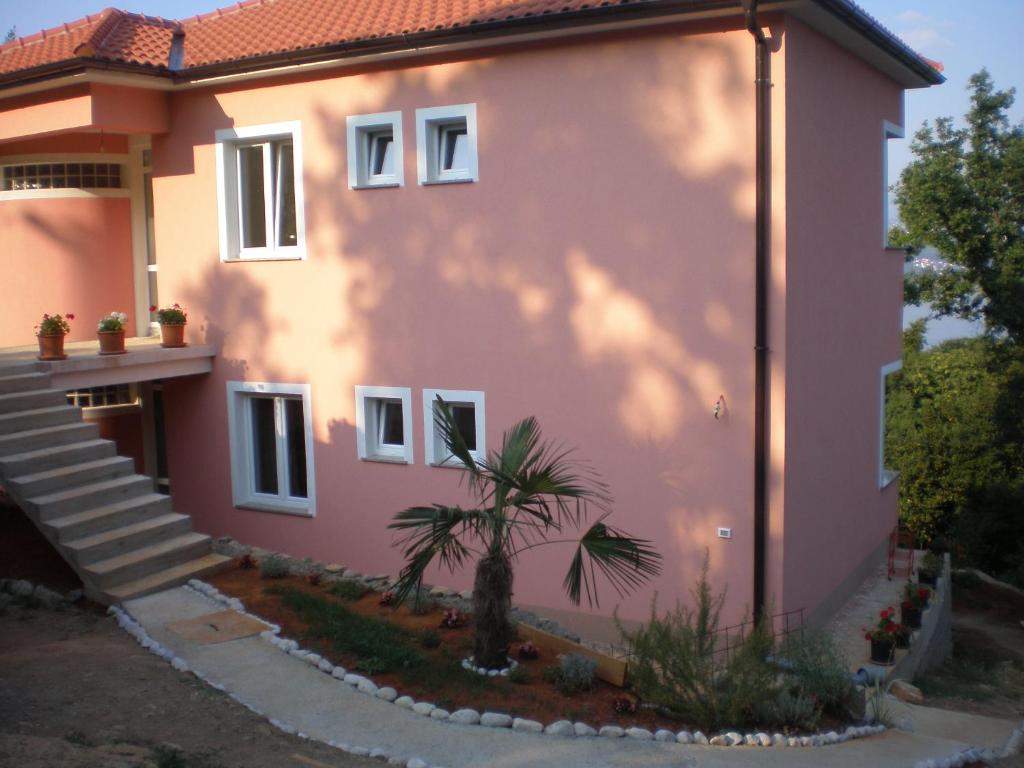 une maison rose avec un palmier devant elle dans l'établissement Apartman Nekić, à Opatija