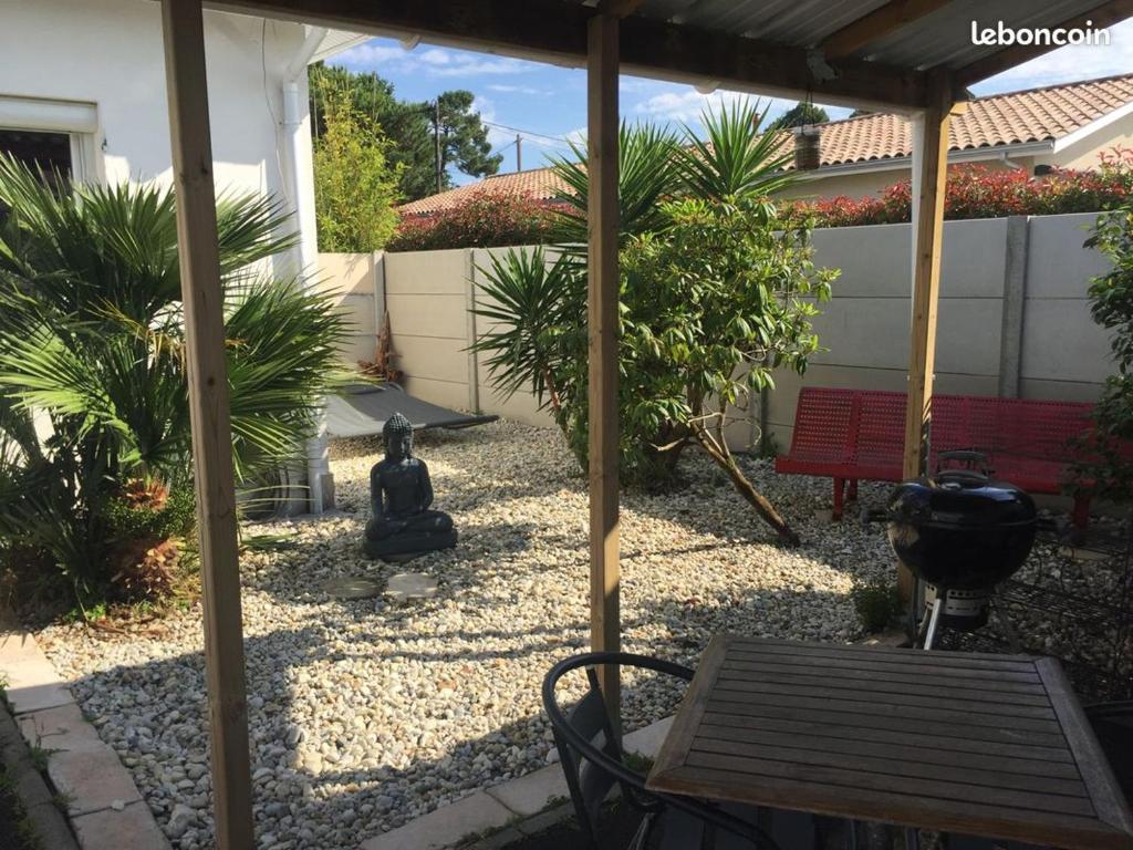 d'une terrasse avec une table et un banc dans une cour. dans l'établissement Maison du bois, à Andernos-les-Bains