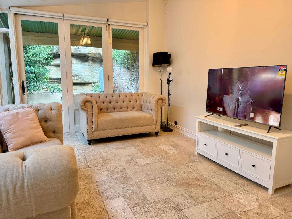 Una sala de estar con un televisor de pantalla plana grande. en Kent St Townhouse, en Sídney