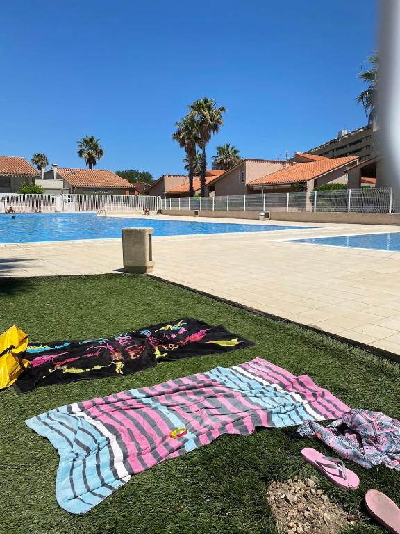 une pile de vêtements posée sur l'herbe à côté d'une piscine dans l'établissement Bel appartement côté Port avec Piscine & Tennis proche Plage, à Saint Cyprien Plage