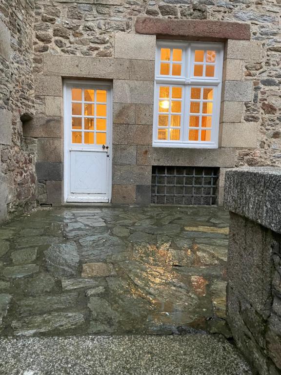 ein Gebäude mit einer weißen Tür und einem Fenster in der Unterkunft Appart COQUET Intra-Muros façade historique rez de chaussée terrasse in Saint-Malo