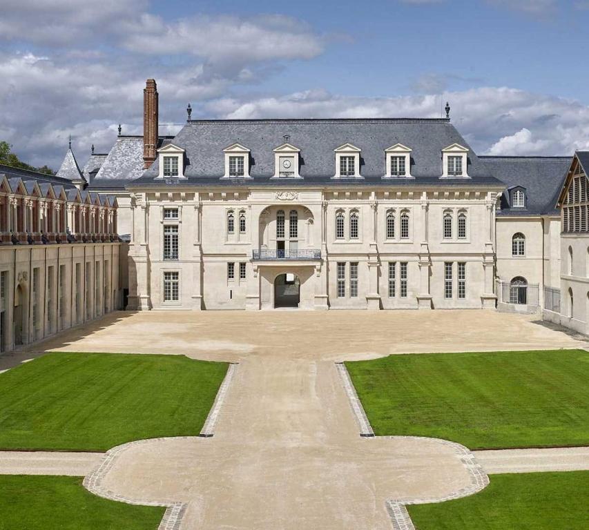 a large white mansion with a large courtyard at Un appartement en centre ville , à 2 pas du château de Villers Cotterets in Villers-Cotterêts