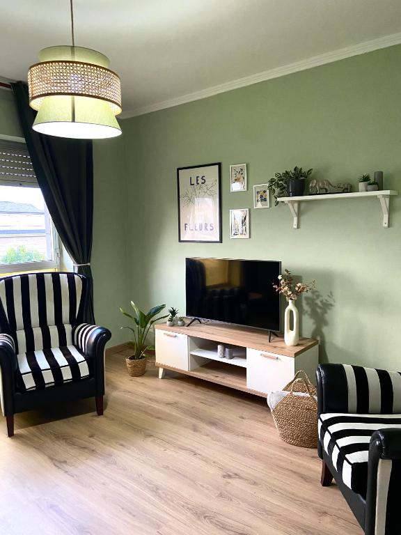 a living room with a flat screen tv and two chairs at A casa da Sia in Ribadeo