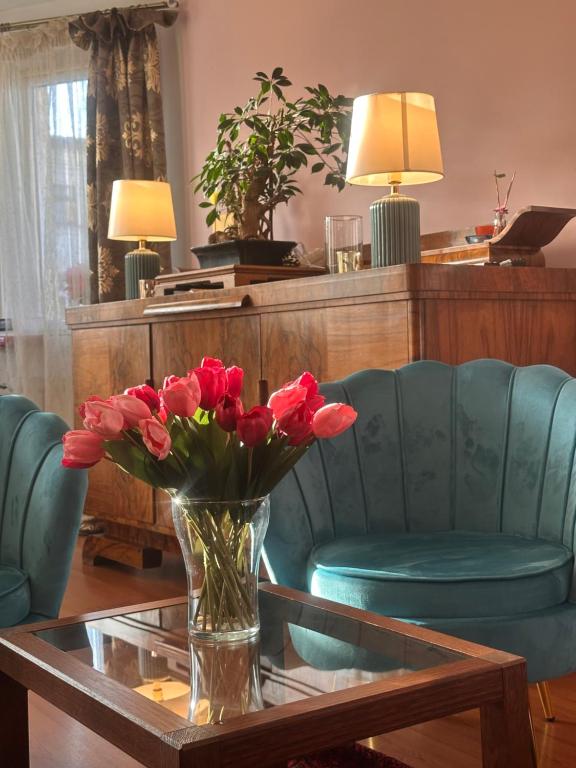 a vase of red flowers sitting on a coffee table at Apartament Diana - Traugutta Wrocław in Wrocław