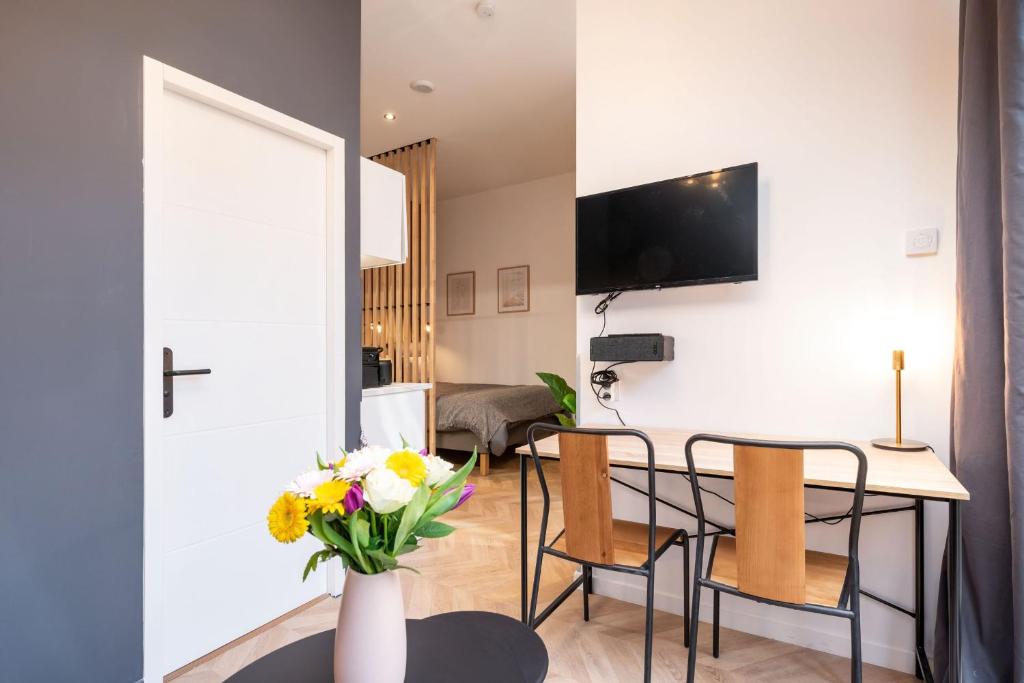 a living room with a table and chairs and a tv at L'héritage & SPA in Lyon