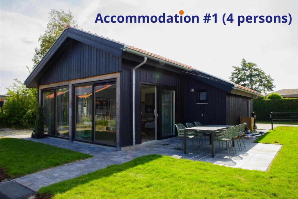 ein schwarzes Haus mit einem Tisch im Hof in der Unterkunft Luxe 10-persoons vakantiehuis Lauwersmeer, Friesland in Anjum