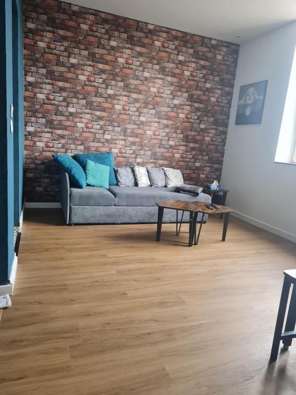 un salon avec un canapé et un mur de briques dans l'établissement F2 chez Cathy et Mike wittenheim, à Wittenheim