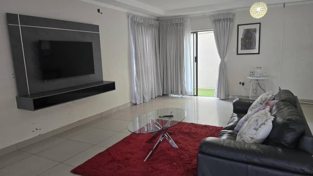 a living room with a couch and a glass table at Moalafivilla Properties, Block 10, 3 Beds House in Gaborone