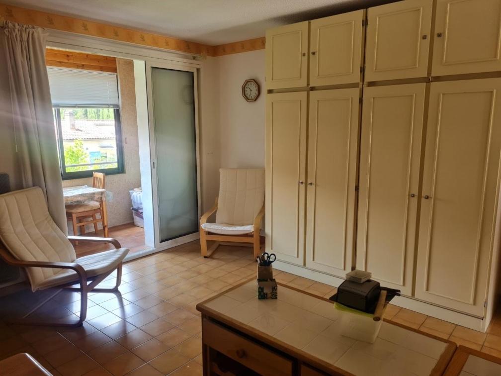 - un salon avec des armoires blanches et une table dans l'établissement la petit cure, à Gréoux-les-Bains