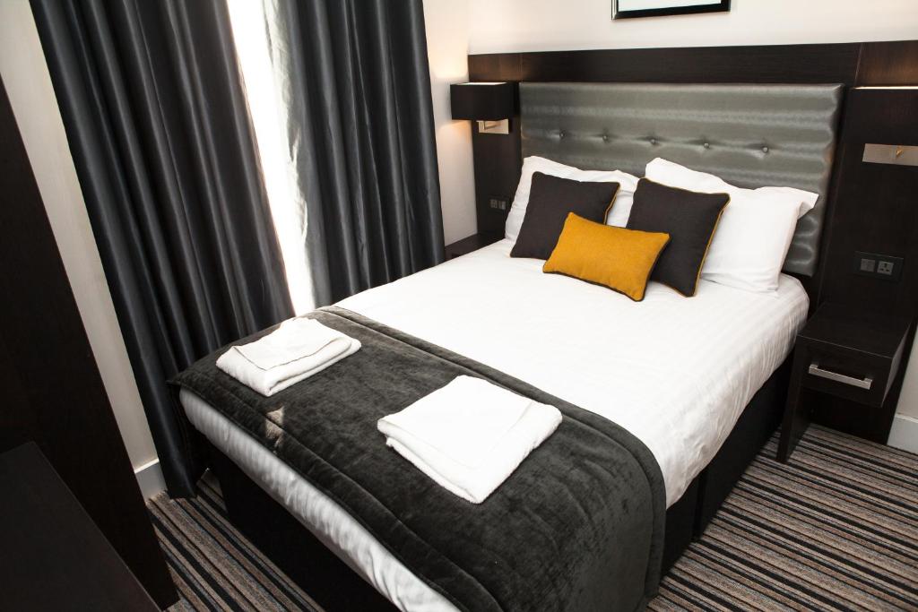 a hotel room with a large bed with yellow and black pillows at The Tudor Inn Hotel in London