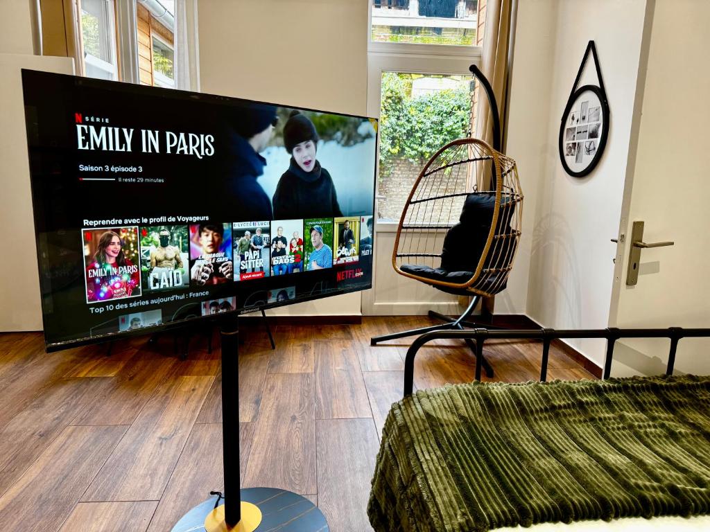 une grande télévision à écran plat dans un salon dans l'établissement La Suite green Douai, à Douai