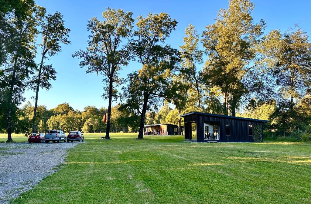 a small cabin with cars parked in a park at La Casa del Bosque in Neltume