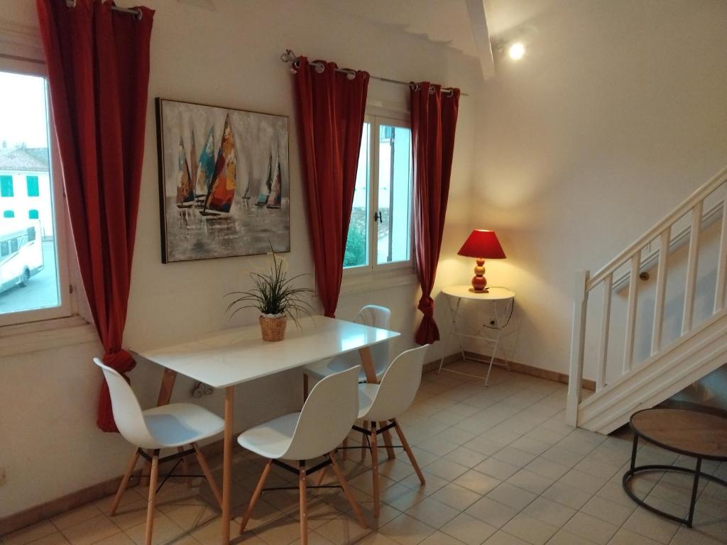 une salle à manger avec une table et des chaises blanches dans l'établissement Les Flamants, 180 m de la Plage, à Saintes-Maries-de-la-Mer