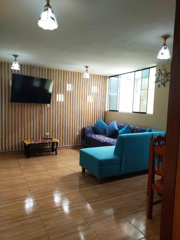 a living room with a blue couch and a flat screen tv at Samay Wasi in Ayacucho