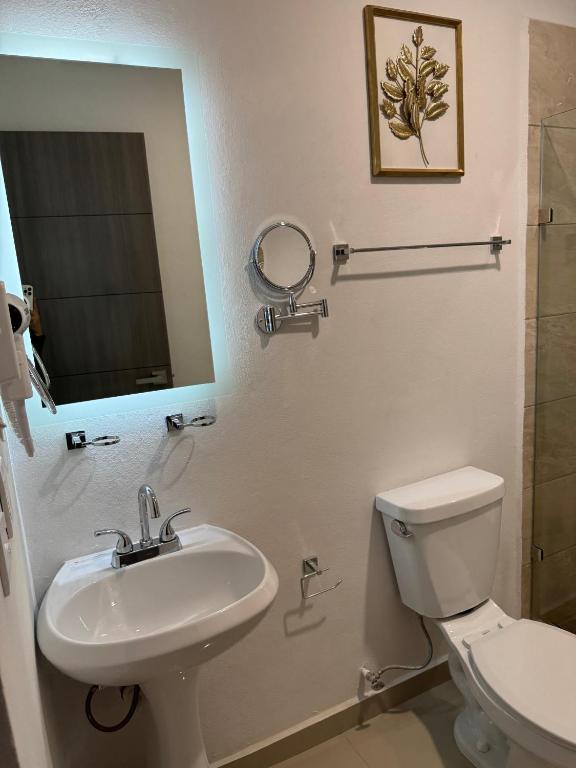 uma casa de banho com um lavatório, um WC e um espelho. em Hotel Faava em Mazatlán
