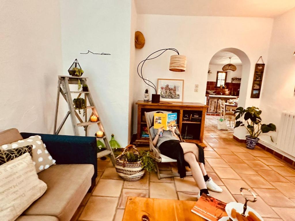 a woman laying on a chair in a living room with a book at Rez de jardin au calme dans le parc des calanques in La Ciotat