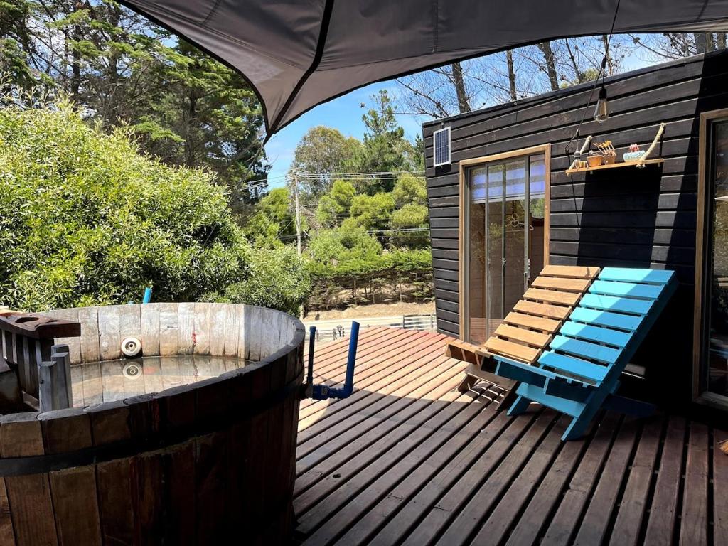 una casa pequeña con un banco azul en una cubierta en Tiny house Hostal, en Pichilemu