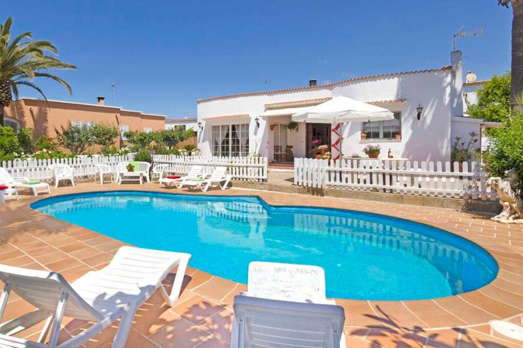 a swimming pool with chairs and a house at Villa Joel - Casa con piscina cerca de la playa in Son Carrio