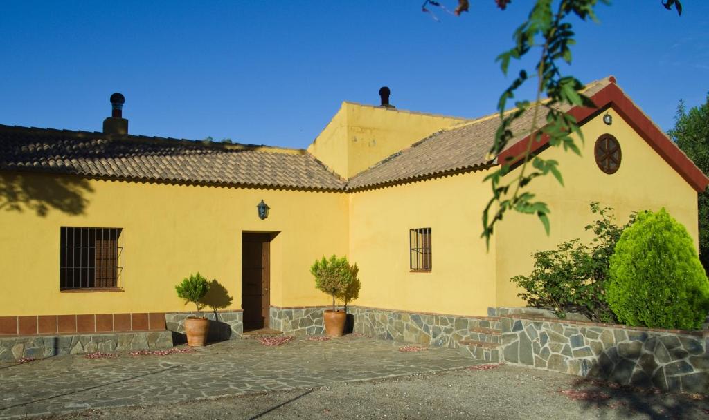 una casa amarilla con dos árboles delante de ella en Rural Montes Málaga: Lagar Don Sancho, en Málaga