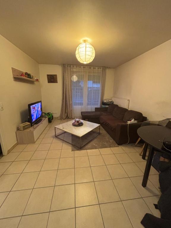 un salon avec un canapé et une télévision dans l'établissement T2 proche Paris 18eme, au Blanc-Mesnil
