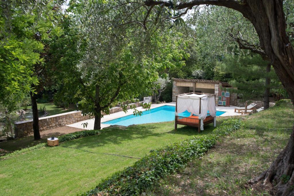 a swimming pool in a yard with a chair next to it at Les chambres du Restaurant le Castellaras - Teritoria in Fayence