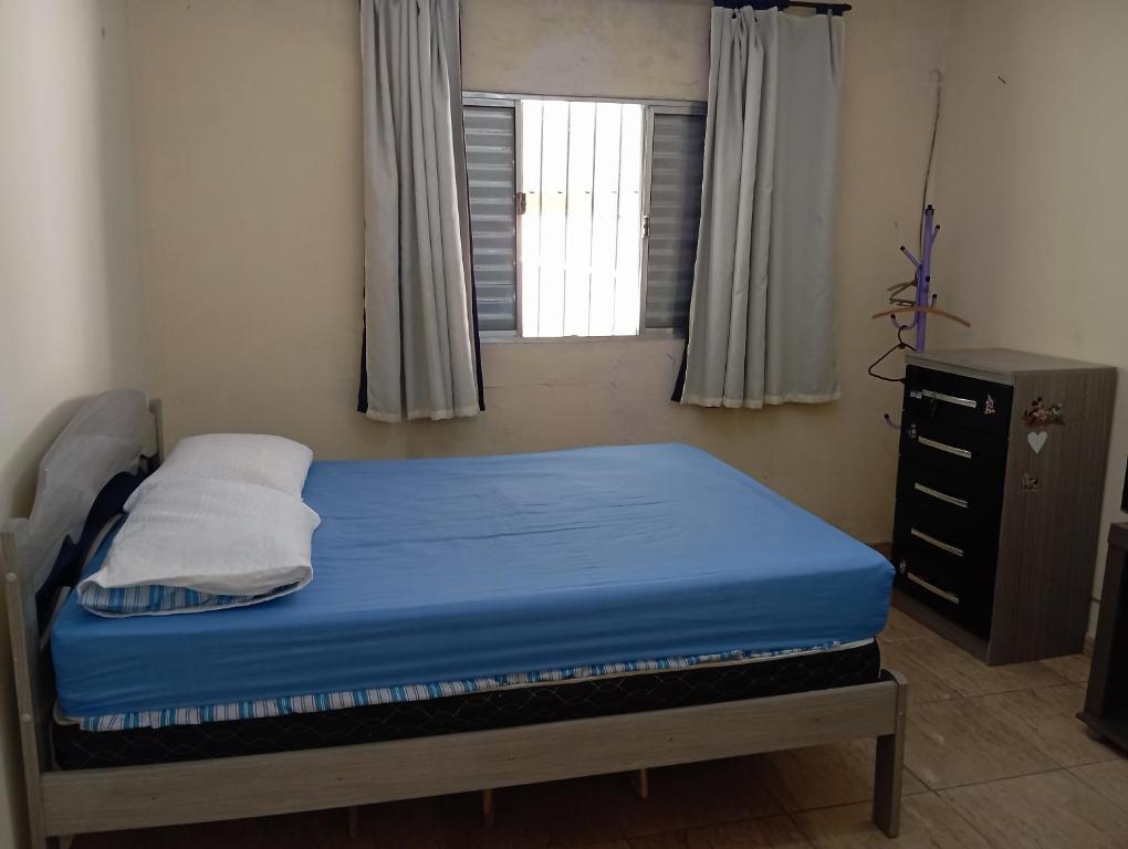 a bedroom with a bed with a blue mattress and a window at Casa completa Estância Turística de Ribeirão Pires in Ribeirão Pires