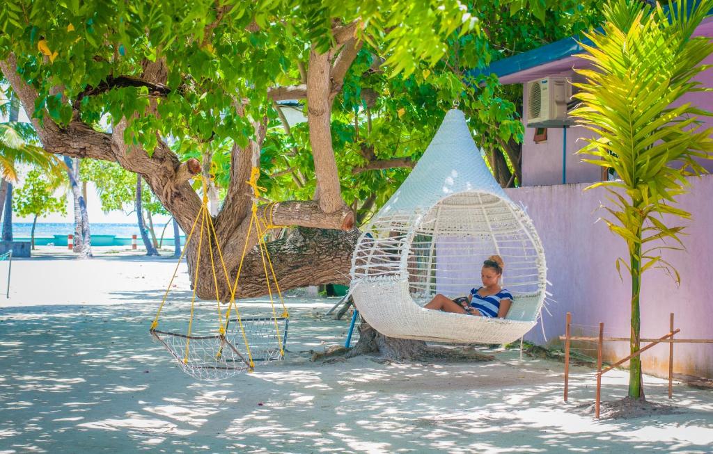 Un joven sentado en una hamaca en un árbol en Jail Break Surf Inn, en Himmafushi