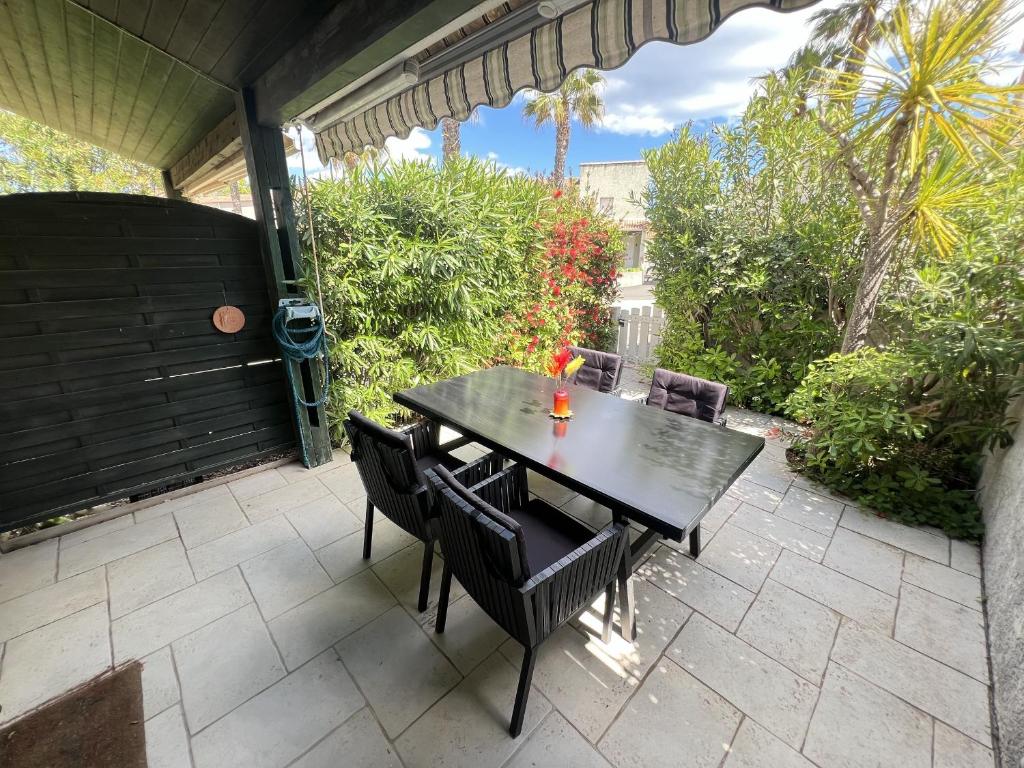 une table noire et des chaises sur une terrasse dans l'établissement Pavillon 6 pers en Résidence avec Piscine et WIFI à 700m de la Plage - FR-1-781-86, à Valras-Plage