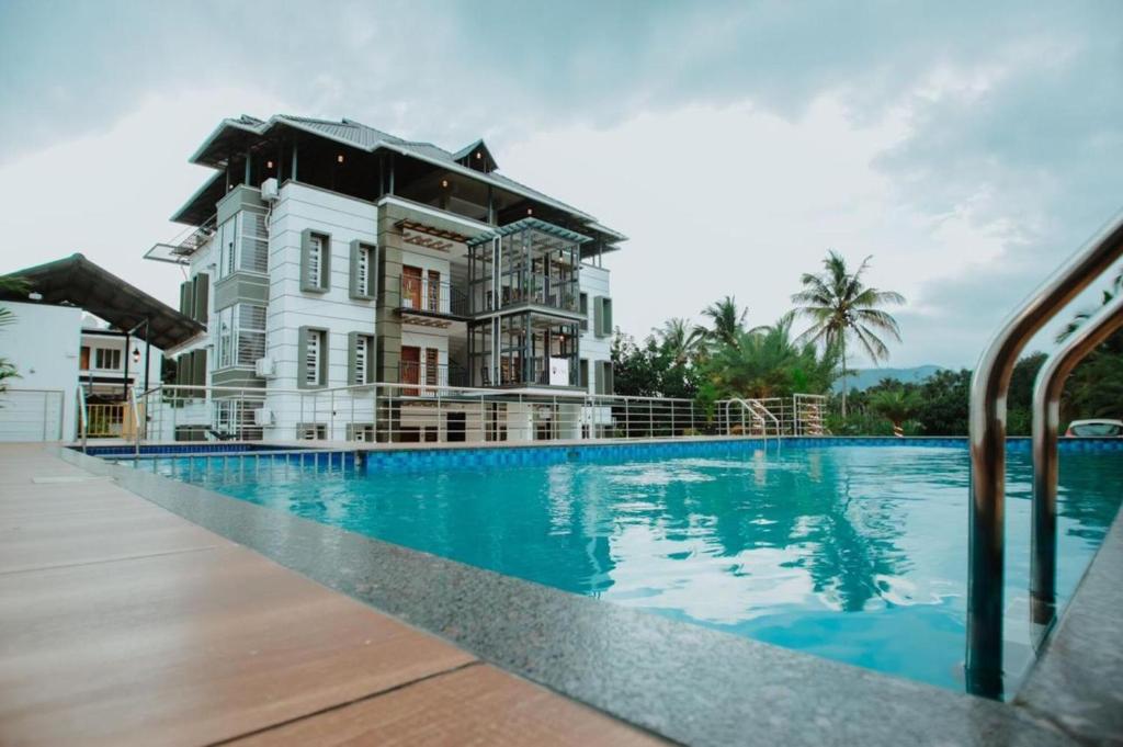a large white house with a swimming pool at Crystal Winter Arcade Wayanad Premium Pool Stay in Wayanad