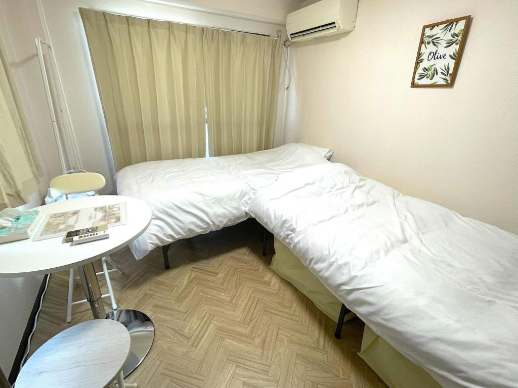 a small room with two beds and a table at Docaホテル セルフチェックイン in Fukuoka