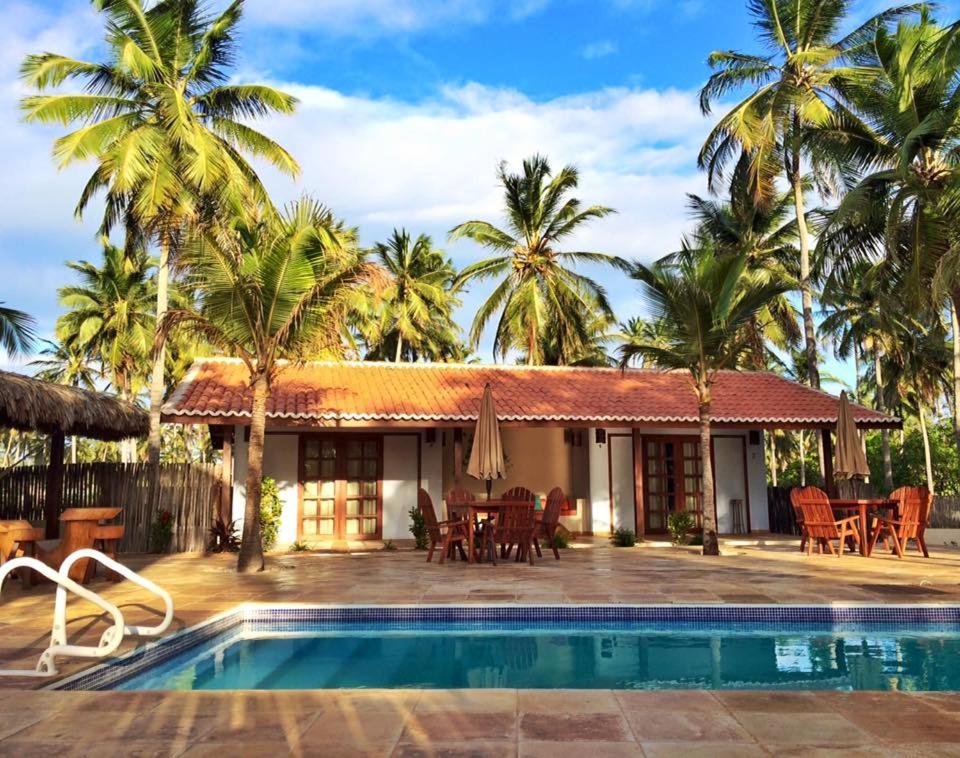 uma casa com piscina e palmeiras em Pousada Vila Icaraí em Icaraí
