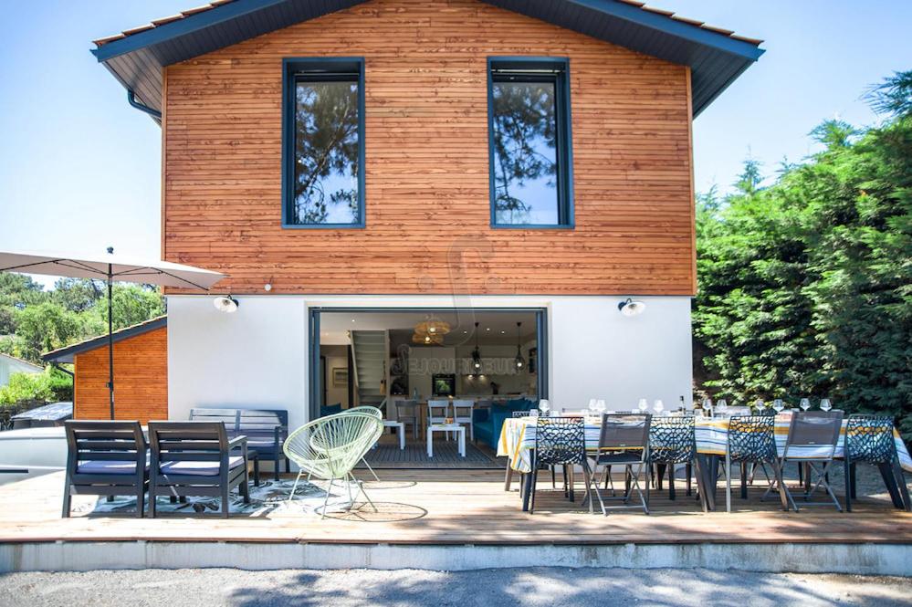 un groupe de tables et de chaises devant un bâtiment dans l'établissement Belle villa moderne sous les pins au Moulleau, à La Teste-de-Buch