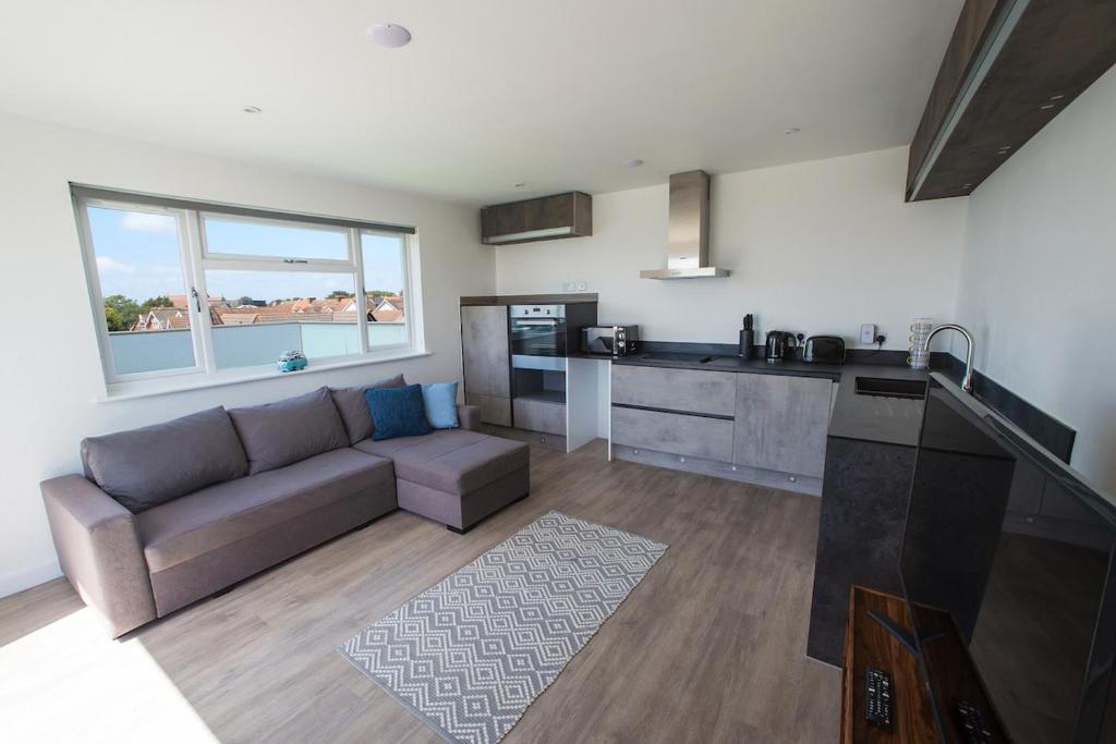a large living room with a couch and a kitchen at Surfside Penthouse in Bournemouth