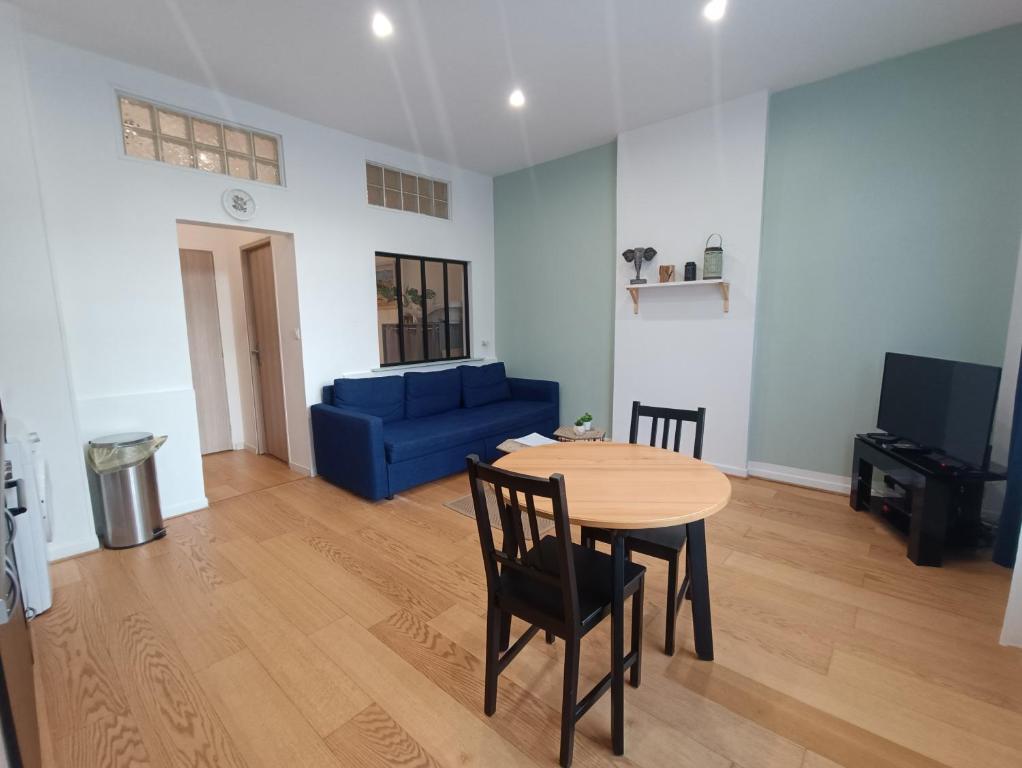 un salon avec une table et un canapé bleu dans l'établissement Appartement calme proche de la mer, à Dunkerque