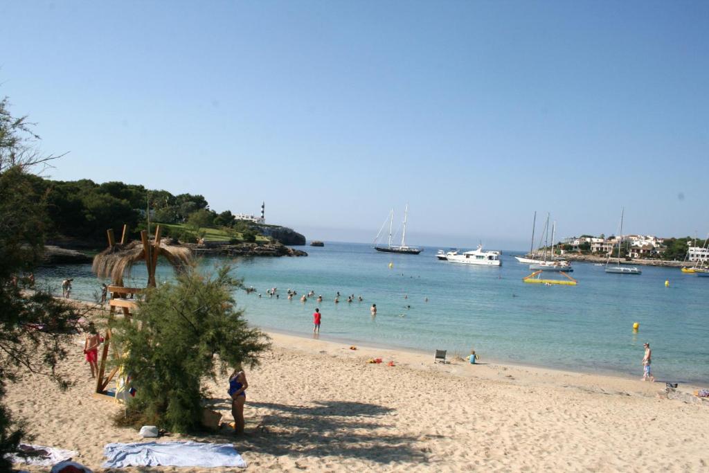 een groep mensen op een strand met boten in het water bij Villa Garrido in Portocolom