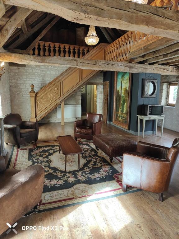 Il comprend un salon doté d'un mobilier en cuir et d'un escalier. dans l'établissement Colombier du Saulce, à Escolives-Sainte-Camille