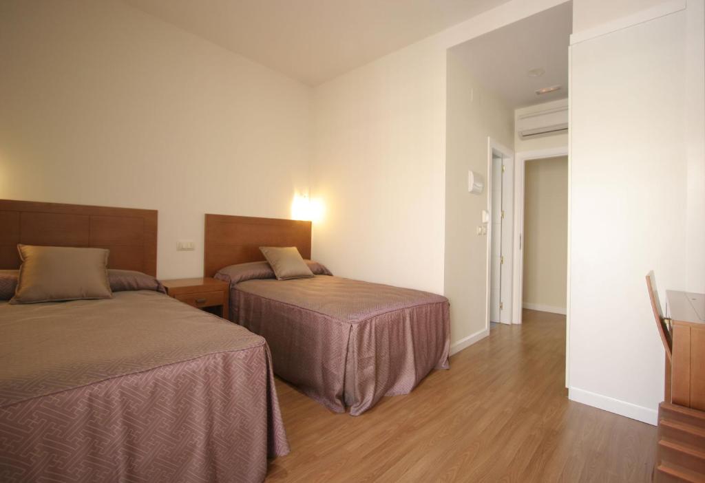 a hotel room with two beds and a hallway at Rincón de Gran Vía in Madrid