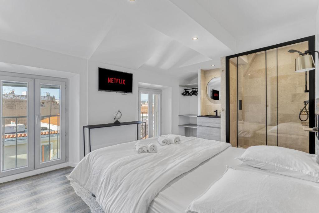 - une chambre avec un grand lit blanc et une horloge murale dans l'établissement F3 Centre de Cannes proche du Palais, à Cannes