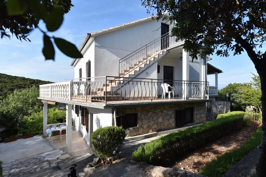a white house with a balcony with a dog on it at Apartmani Marko in Gdinj