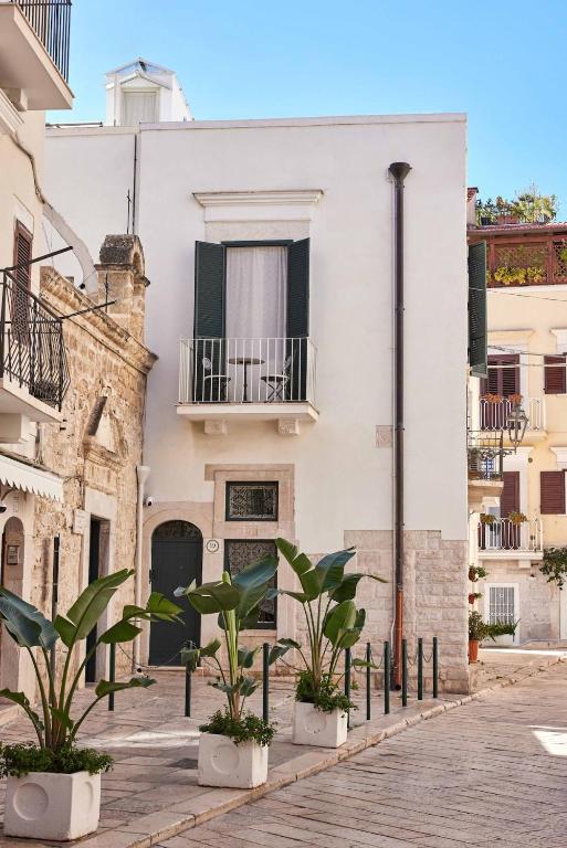 a white building with potted plants on a street at Dimora Storica a Trani con Terrazzo Jacuzzi x Dimora Storica a Trani con Terrazzo e Jacuzzi con 6 Posti Letto e Aria Condizionata in Trani