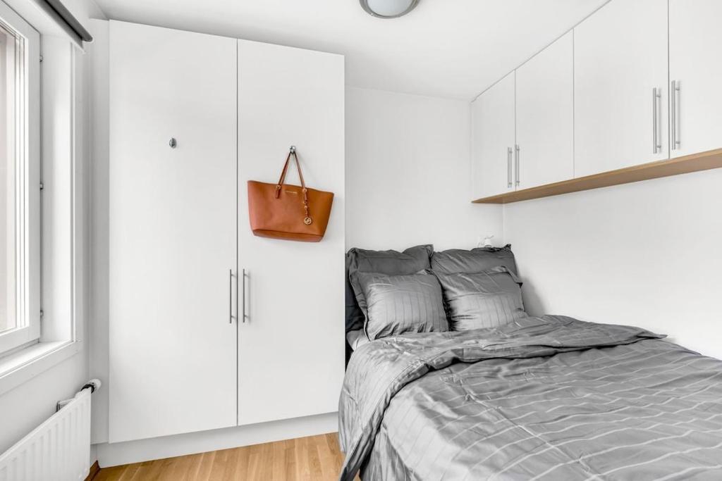 Un dormitorio blanco con una cama y armarios blancos. en Penthouse in Trondheim, Solsiden, en Trondheim