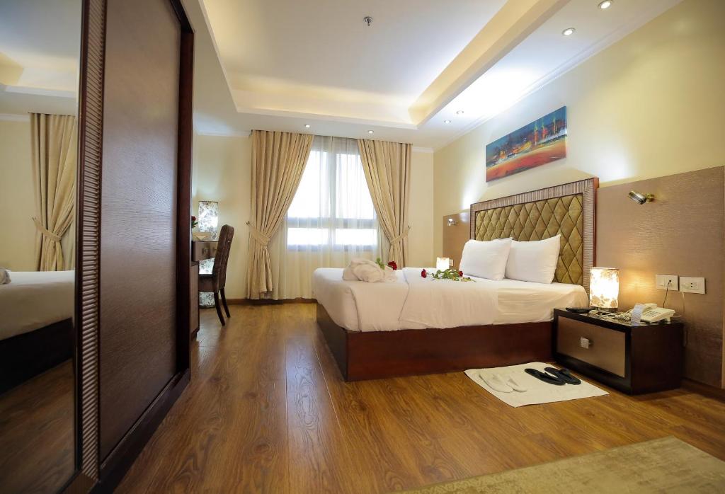 a hotel room with a large bed and a window at Cairo Taj Hotels & Suites - Dokki in Cairo