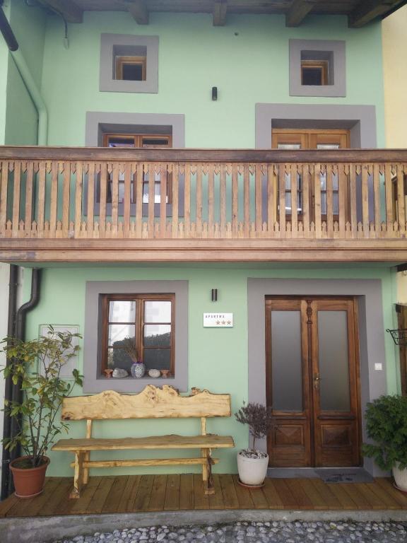 a wooden bench in front of a house with a balcony at Apartment Bernarda - Entire House in Kobarid