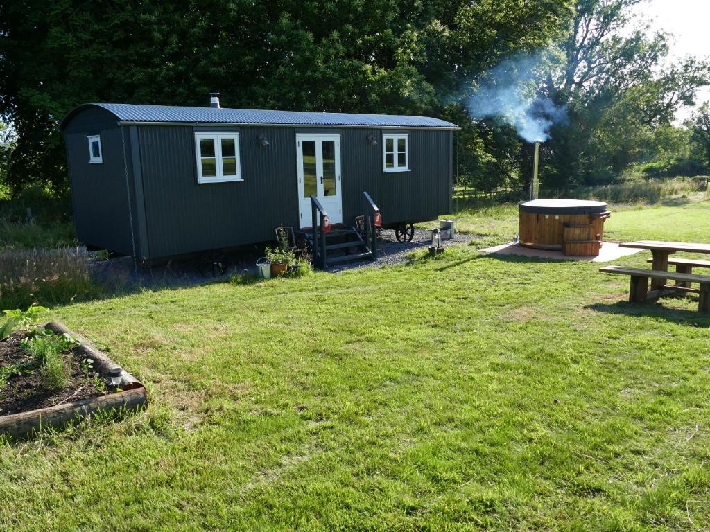 a green tiny house in a yard with a picnic table at Ravenscroft Retreats Glamping Llandeilo in Golden Grove